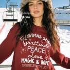 A woman wearing 'CHRISTMAS SPIRIT Gratitude PEACE Love MAGIC & HOPE Sprinkle with Joy' unisex sweatshirt.

Original design and copyright by first row LA August 10th, 2026.