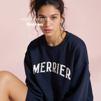 A woman wearing a bright pink crewneck sweatshirt with 'MERRIER' printed in white arched letters across the chest.

Original design and copyright by first row LA, August 11th 2026.