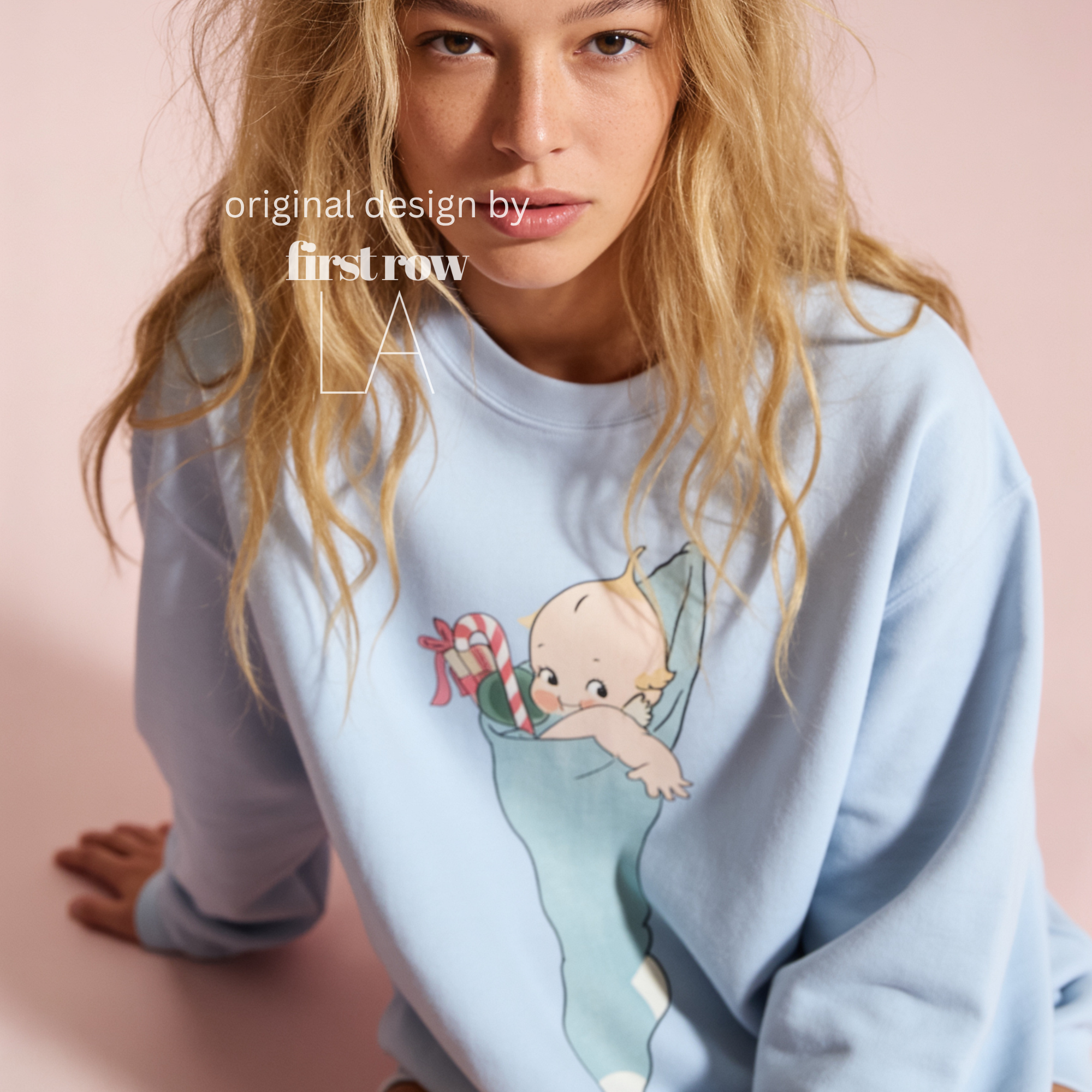 A woman wearing a light blue sweatshirt with a cartoon baby graphic.

Original design and copyright by first row LA, august 12th 2026.
