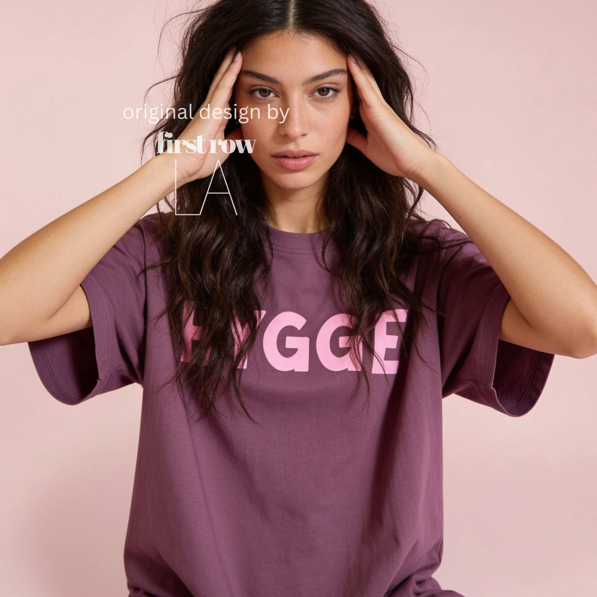 Woman wearing HYGGE T-shirt  with  large pink hand drawn letters.

Original design and copyright by first row LA Aught 18th, 2026.
