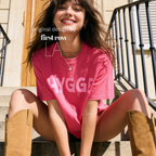 Woman wearing HYGGE T-shirt  with  large pink hand drawn letters.

Original design and copyright by first row LA Aught 18th, 2026.