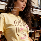 A woman wearing a graphic T-shirt with a cat illustration and the words 'DON'T SHOP ADOPT'.

Original design and copyright by first row LA 2021.