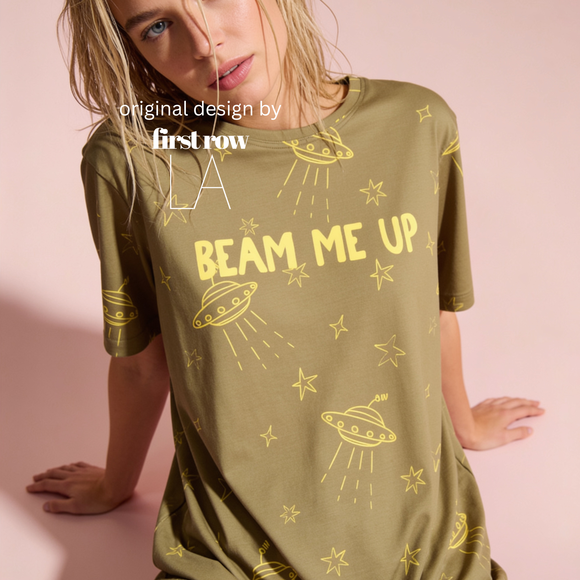 A woman wearing an olive green short-sleeve t-shirt with yellow UFO and star graphics and the text 'BEAM ME UP'.