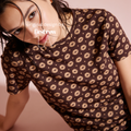 A woman wearing a brown short-sleeve t-shirt with a repeating beige lip print.

Original design and copyright by first row LA.