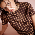 A woman wearing a brown short-sleeve t-shirt with a repeating beige lip print.

Original design and copyright by first row LA.