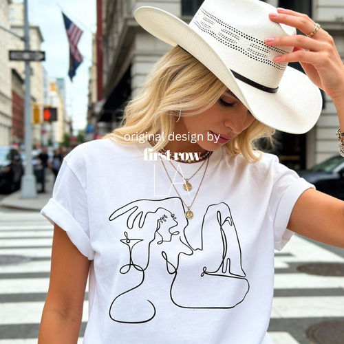 Woman wearing Cowgirl Martini Shirt, Cowboy Boots Tee, Western Graphic T-Shirt, Country Concert Outfit, Nashville Bachelorette Tee, Rodeo Cowgirl Gift. 

Designed and © 2025 by Lilo on Paper, only sold at First Row LA.