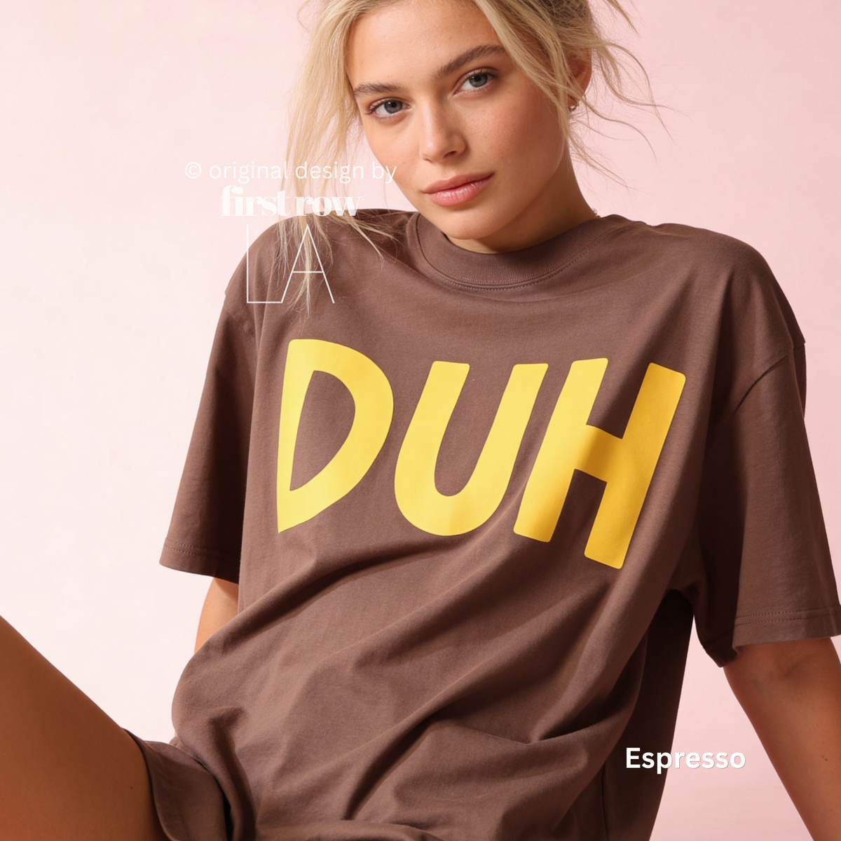 A woman wearing an oversized brown t-shirt with the word 'DUH' printed in large yellow letters across the chest.

Original design and copyright by first row LA, August 4th 2026.