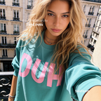 A woman in Paris wearing a teal crewneck sweatshirt with large pink 'DUH' lettering across the front. 

Original design and copyright by first row LA, August 4th 2026.