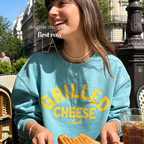 Woman wearing Grilled Cheese Shirt, Club Sweatshirt, Funny Foodie, Comfort Food Shirt, Cheese Lover Gift, Retro Diner Graphic, Unisex Pullover, Y2K Shirt.

Original design and copyright by first row LA 2026.