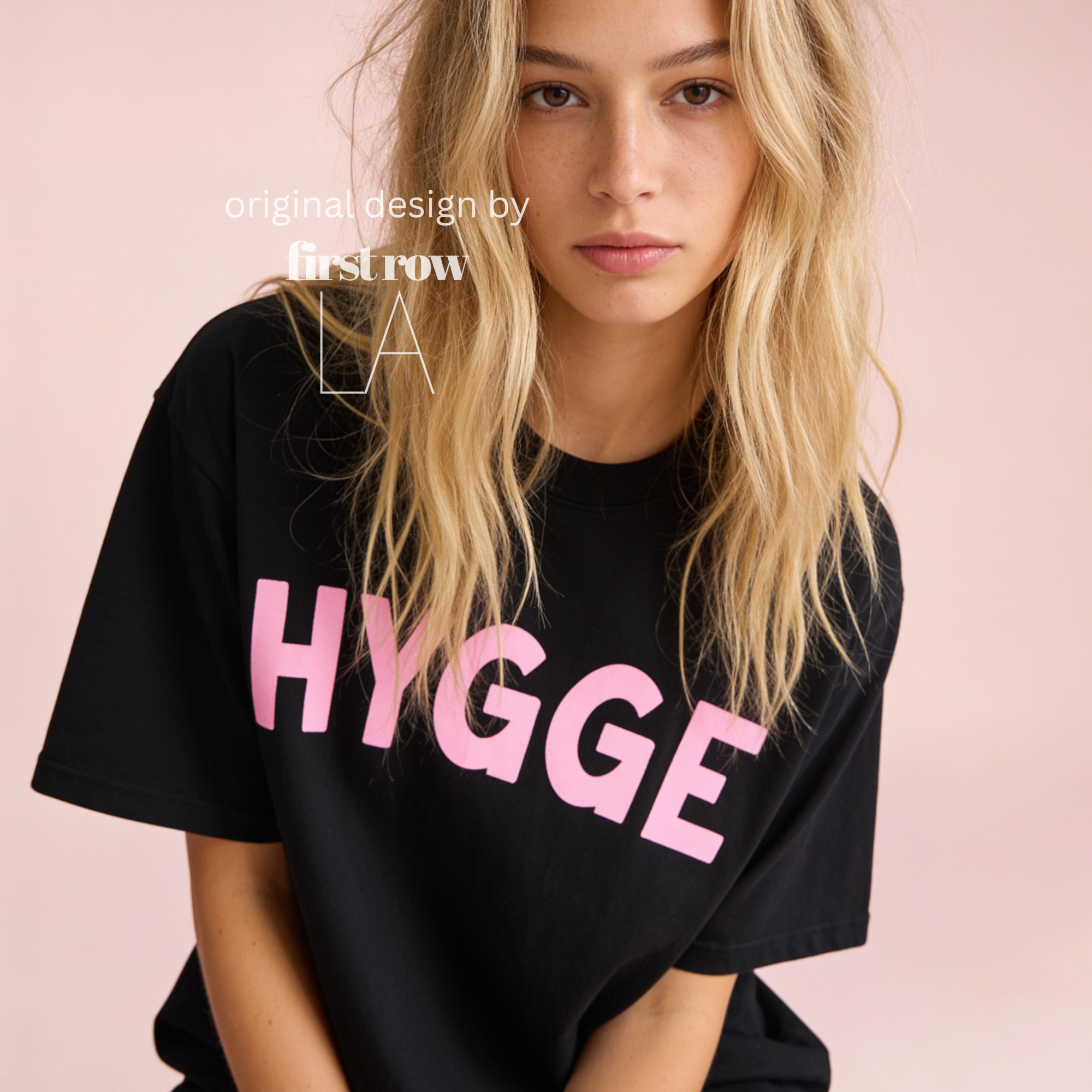 Woman wearing HYGGE T-shirt  with  large pink hand drawn letters.

Original design and copyright by first row LA Aught 18th, 2026.