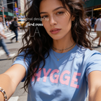 Woman wearing HYGGE T-shirt  with  large pink hand drawn letters.

Original design and copyright by first row LA Aught 18th, 2026.