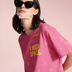 A woman wearing black sunglasses and a pink graphic T-shirt with yellow space-themed illustrations and the text 'I NEED SPACE'. Original design by first row LA.
