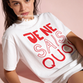 A woman wearing a white oversized T-shirt with large red French text reading 'JE NE SAIS QUOI, France 1990'. Original design by first row LA.