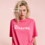 A blonde woman wearing an oversized bright pink t-shirt with the white text 'Miss BEHAVING' printed across the chest. Original design by first row LA.