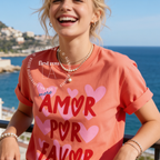 Woman wearing More Amor Por Favor Shirt, Summer Graphic Tee, Pink Heart T-Shirt, Cute Spanish Shirt, Retro Vacation Tee, Beach Lover Shirt, Love More Tee