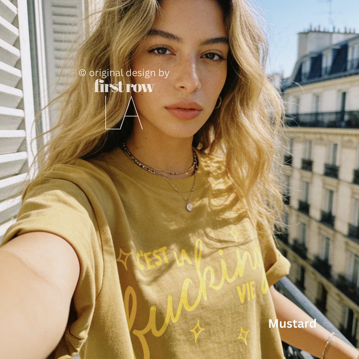 Woman wearing 'C'est la fucking vie' T-shirt with small yellow star accents. 

Original design and copyright by first row LA, August 4th 2026.