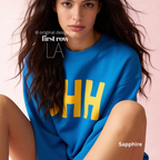 A model wearing a bright blue sweatshirt with large yellow block letters spelling 'SHH' across the chest.

Original design and copyright by first row LA, August 4th 2026.