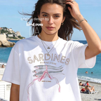 A woman wearing a white graphic T-shirt with 'SARDINES A LA HULE D'OLIVE, produit de France' and an original watercolor fish illustration.

Original design by first row LA.
Copyright lilo on paper 2025.