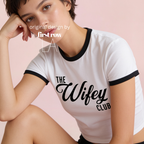 A woman wearing a white cropped ringer T-shirt with black trim and the words 'THE Wifey CLUB' printed in black across the front.

Original design and copyright by first row LA.