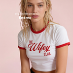 A woman wearing a white cropped ringer T-shirt with red trim and the words 'THE Wifey CLUB' printed in red across the front.

Original design and copyright by first row LA.