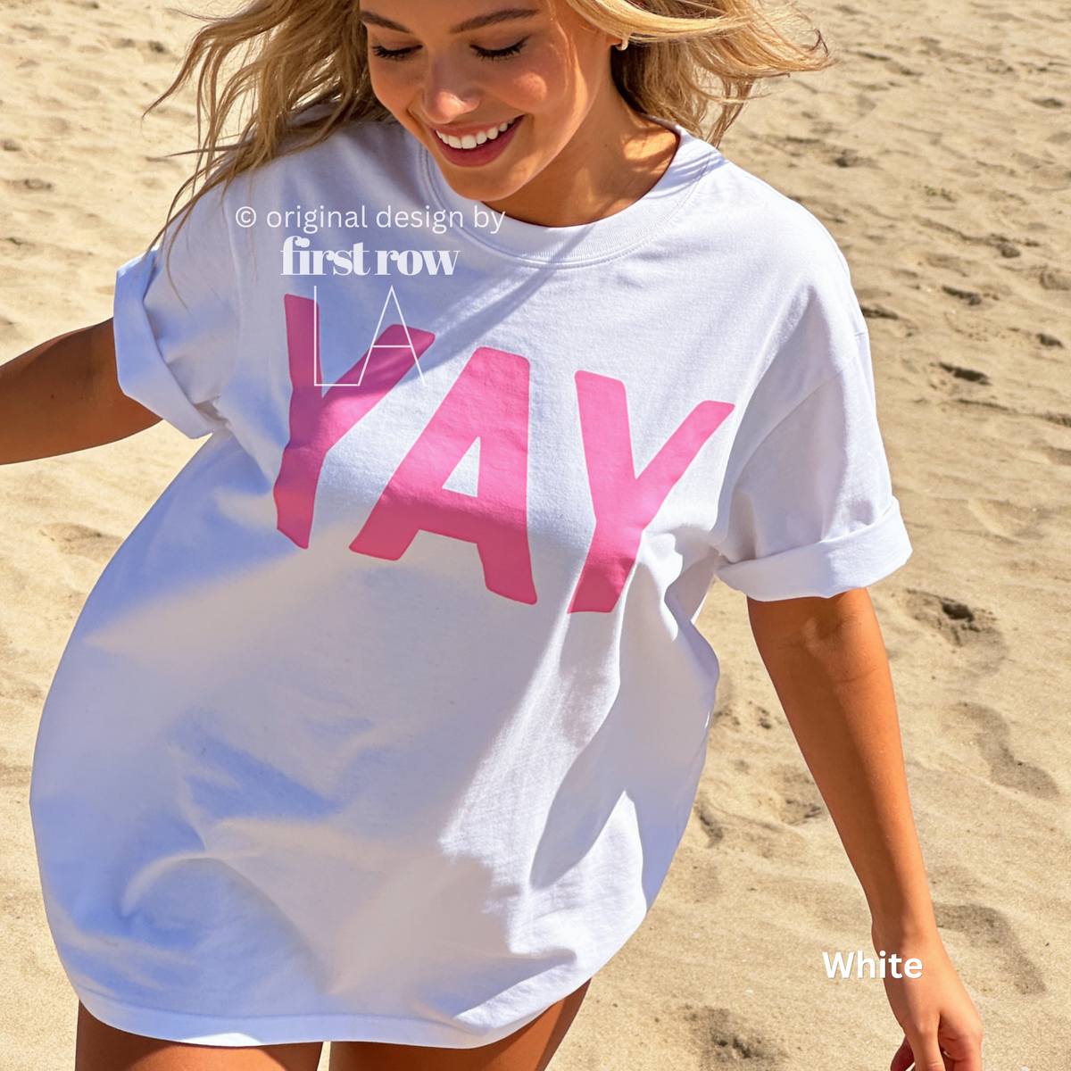 A woman wearing a white t-shirt with pink YAY print.

Original design and copyright by first row LA 2026