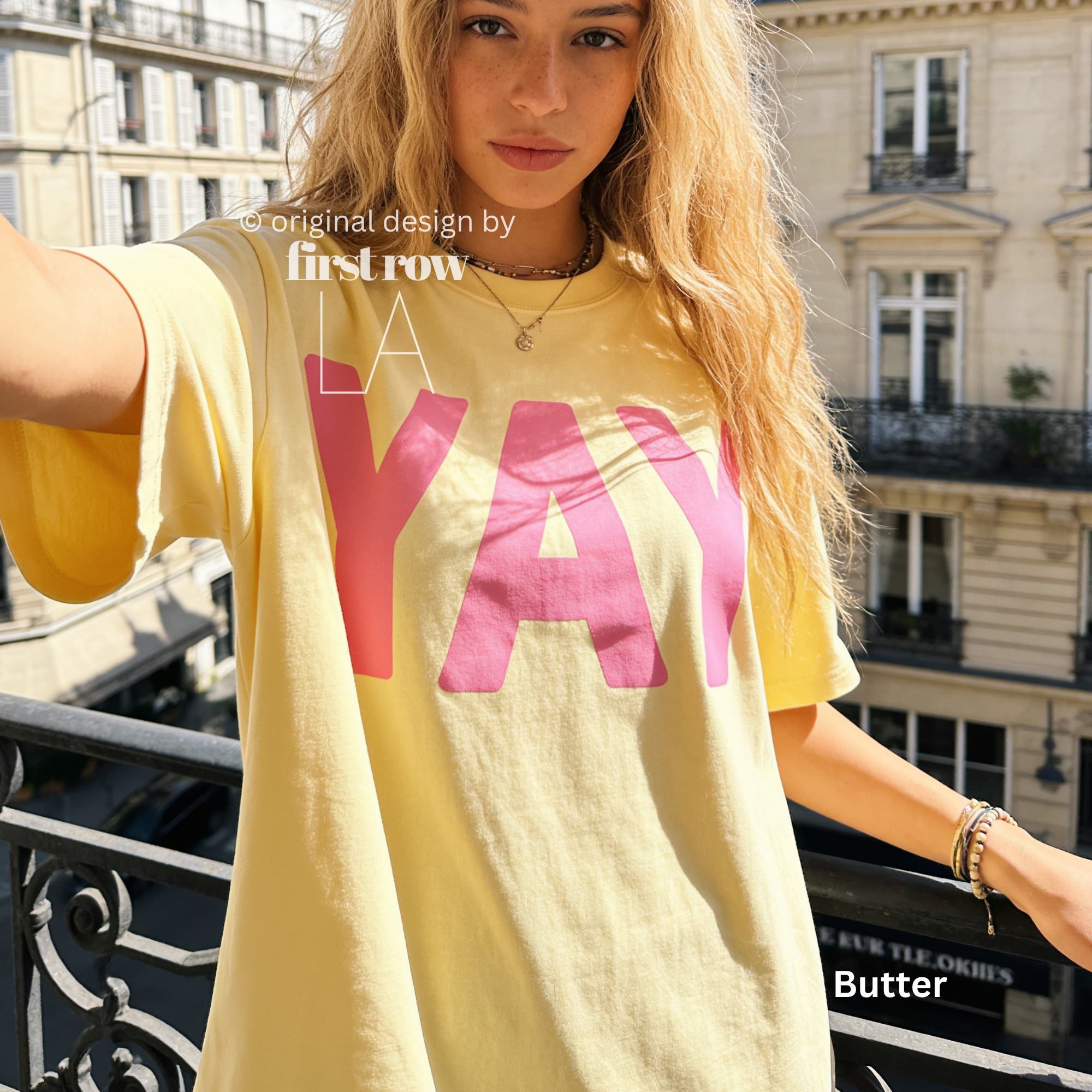 A woman wearing a bright yellow t-shirt with pink YAY print.

Original design and copyright by first row LA 2026