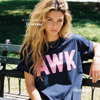A woman sitting on a park bench wearing an oversized dark blue t-shirt with the word 'AWK' printed in large pink letters across the front. 

Original design and copyright by first row LA, August 4th 2026.