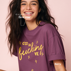 Woman wearing 'C'est la fucking vie' T-shirt with small yellow star accents. 

Original design and copyright by first row LA, August 4th 2026.
