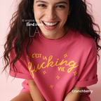 Woman wearing 'C'est la fucking vie' T-shirt with small yellow star accents. 

Original design and copyright by first row LA, August 4th 2026.