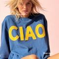 A woman wearing a blue crewneck sweatshirt with large yellow 'CIAO' print.

Original design and copyright by first row LA 2026