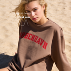 A woman wearing a sweatshirt with 'KØBENHAVN' printed across the chest in dark red collegiate lettering, 

Copenhagen shirt.

Original design and copyright by first row LA.