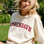 A woman wearing a sweatshirt with 'KØBENHAVN' printed across the chest in dark red collegiate lettering, 

Copenhagen shirt.

Original design and copyright by first row LA.