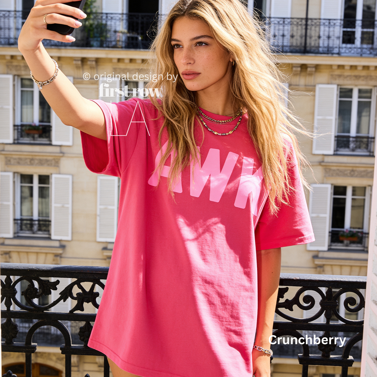 A woman takes a selfie while wearing an oversized bright pink t-shirt with the word 'AWK' in light pink across the chest. 

Original design and copyright by first row LA, August 4th 2026.