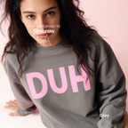 A woman wearing a grey sweatshirt with the word 'DUH' printed in large pink letters across the chest.

Original design and copyright by first row LA, August 4th 2026.