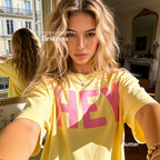 A woman wearing a yellow T-shirt with pink 'HEY' print.

Original design and copyright by first row LA 2026.