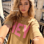 A woman wearing mustard yellow T-shirt with pink 'HEY' print.

Original design and copyright by first row LA 2026.