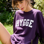 A woman outdoors wearing an oversized purple sweatshirt with the word 'HYGGE' printed across the chest in large white letters. 

Original design and copyright by first row LA.