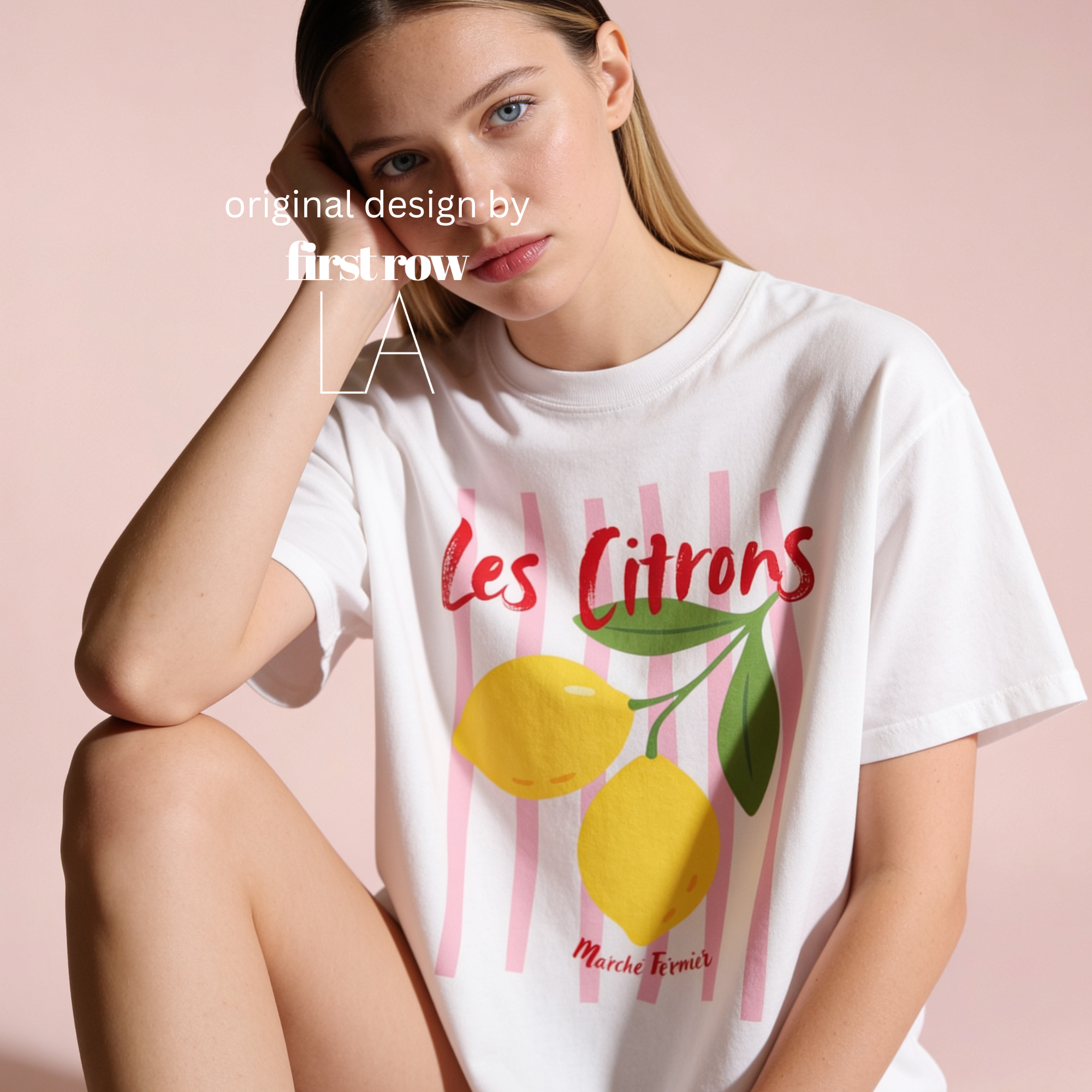 A woman wearing a white graphic T-shirt with pink vertical stripes, red 'Les Citrons, Marcher Fermier' lettering, and yellow lemon illustrations.

Original design and copyright by first row LA 2025.