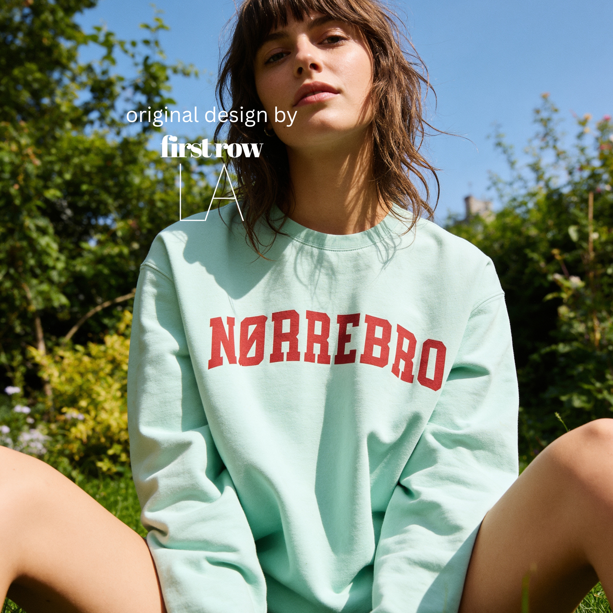 A woman wearing an oversized sweatshirt with 'NØRREBRO' printed across the chest in dark red collegiate lettering.

Original design and copyright by first row LA.