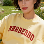A woman wearing an oversized sweatshirt with 'NØRREBRO' printed across the chest in dark red collegiate lettering.

Original design and copyright by first row LA.