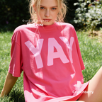 A woman wearing a hot pink t-shirt with light pink YAY print.

Original design and copyright by first row LA 2026