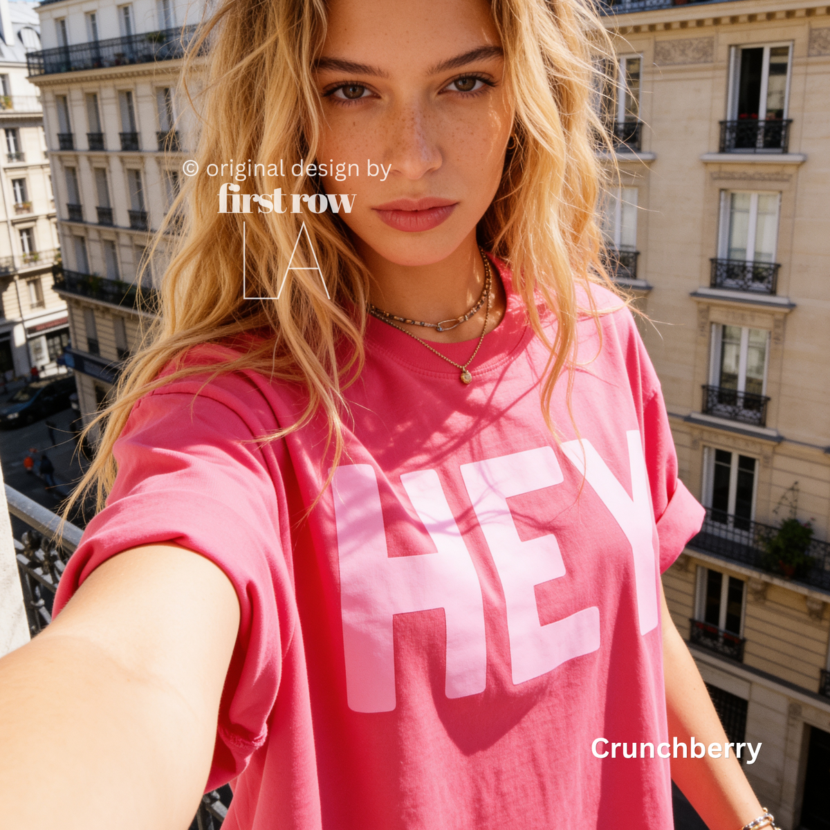 A woman wearing a hot pink T-shirt with pink 'HEY' print.

Original design and copyright by first row LA 2026.