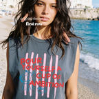 A woman wearing a sleeveless cream-colored t-shirt with a graphic print that reads 'POUR YOURSELF A CUP OF AMBITION' in red, decorated with pink vertical stripes, a blue moka pot, and a small coffee cup. 

Original design and copyright by first row LA.