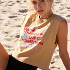 A woman wearing a sleeveless cream-colored t-shirt with a graphic print that reads 'POUR YOURSELF A CUP OF AMBITION' in red, decorated with pink vertical stripes, a blue moka pot, and a small coffee cup. 

Original design and copyright by first row LA.