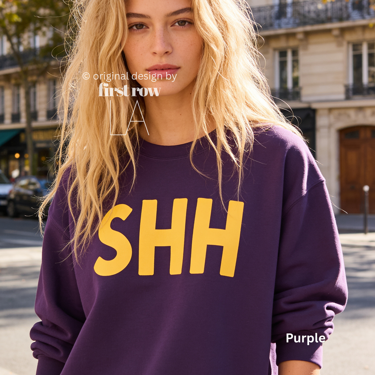 A woman wearing a purple crewneck sweatshirt with large yellow 'SHH' lettering on the front.

Original design and copyright by first row LA, August 4th 2026.