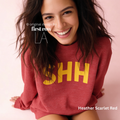 A woman wearing a heathered red sweatshirt with large yellow 'SHH' lettering on the front.

Original design and copyright by first row LA, August 4th 2026.