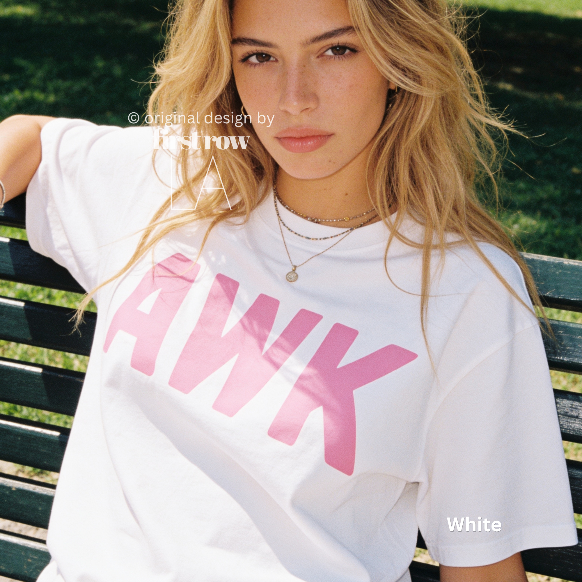 A woman sitting on a park bench wearing a white oversized T-shirt with large pink 'AWK' lettering across the front. 

Original design and copyright by first row LA, August 4th 2026.