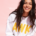 A woman wears a white crewneck sweatshirt with large yellow block letters spelling 'AWK' on the front.

Original design and copyright by first row LA, August 4th 2026.