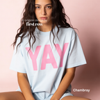 A woman wearing a light blue t-shirt with pink YAY print.

Original design and copyright by first row LA 2026