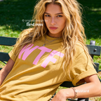 A woman wearing a mustard yellow T-shirt with large pink 'WTF' print.

Original design and copyright by first row LA 2026.